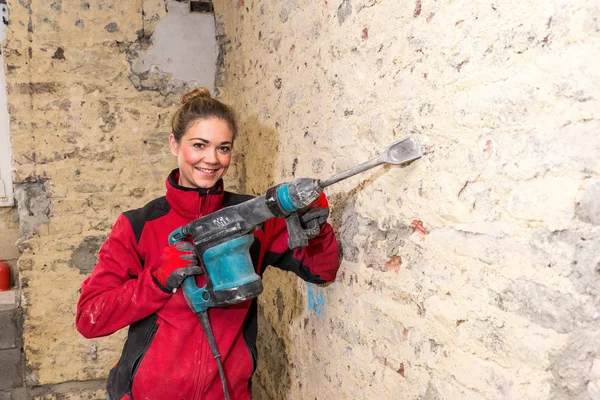 Ambitious craftswoman with caulking hammer in front of brick wal — Stock Photo, Image