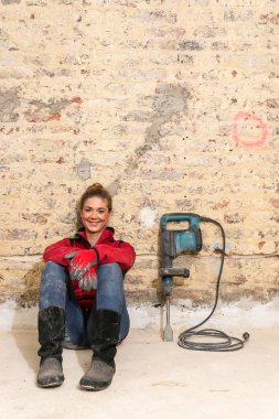 İddialı craftswoman tuğla duvar önünde oturan