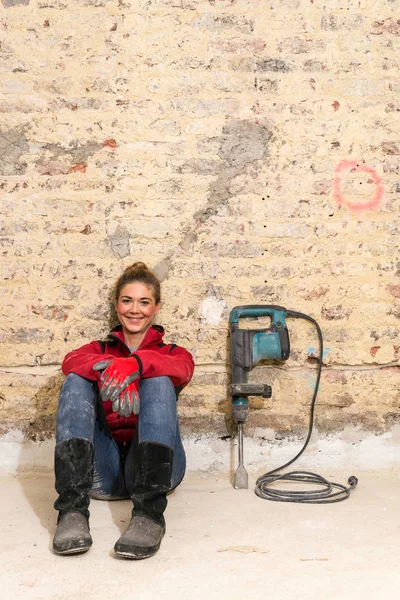 Ambitieuze craftswoman, zittend op de vloer voor bakstenen muur in — Stockfoto