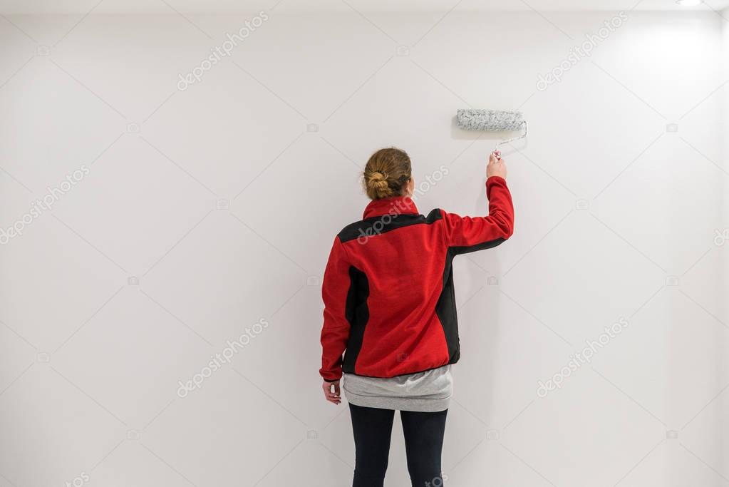 Female painter with paint roller in front of wall as template