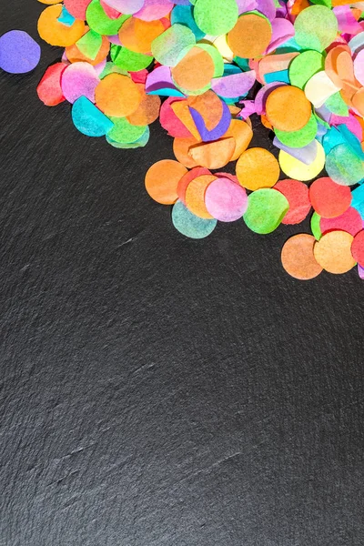 Красочные конфетти на черном сланце в качестве шаблона для празднования — стоковое фото