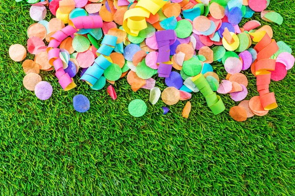 Coloridos confeti y serpentinas sobre hierba como plantilla para celebrar — Foto de Stock