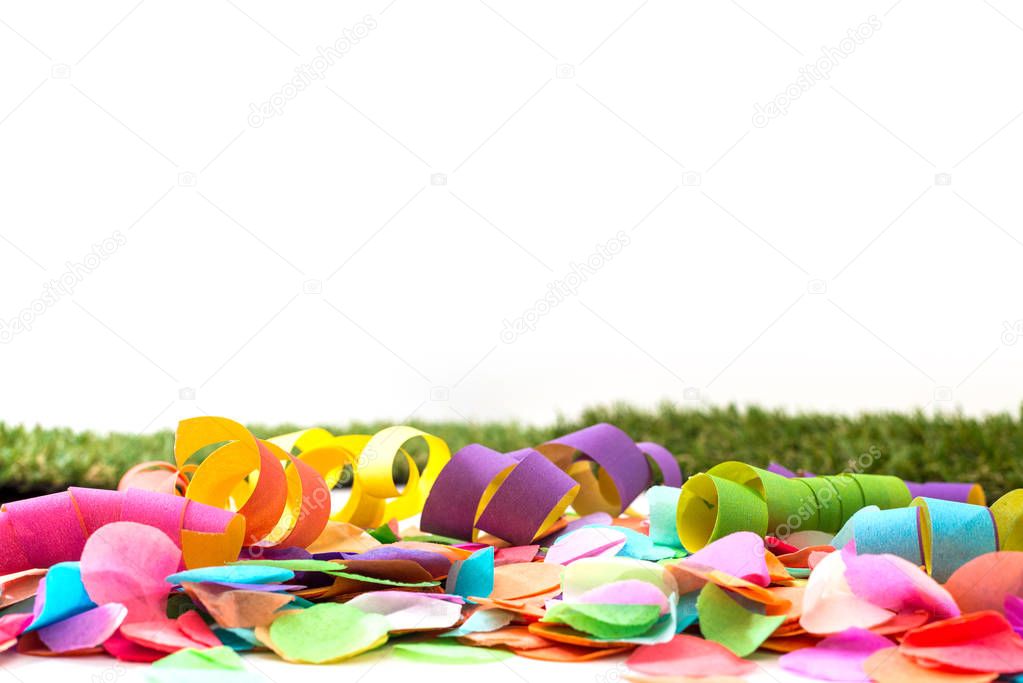 Colorful confetti and streamers on grass in front of background 