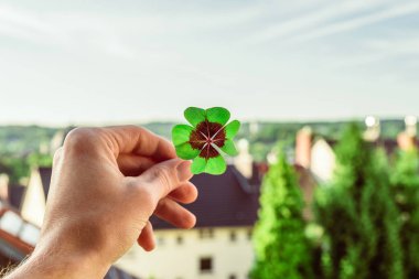 Dört yapraklı yonca şanslı el ile skyline karşı düzenlenen