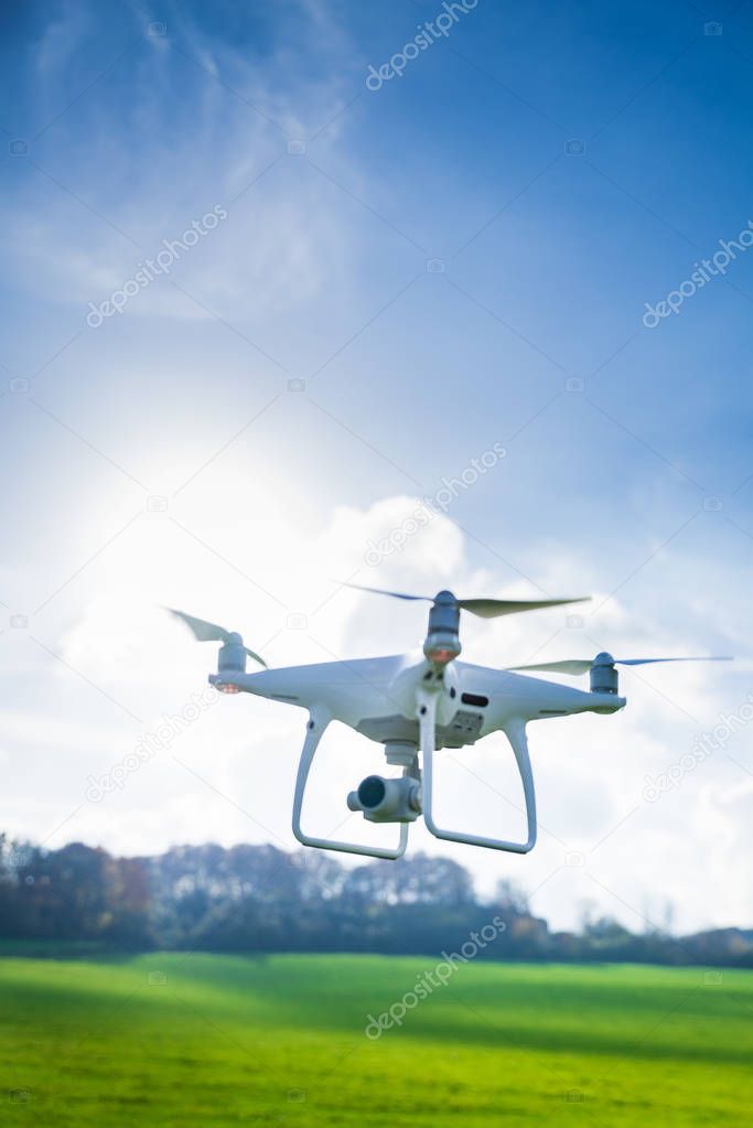 Picture of flying white drone camera in front of trees