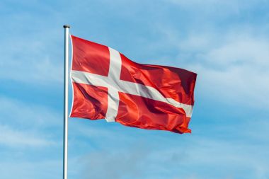 Danish flag waggling in the wind with sky in background clipart