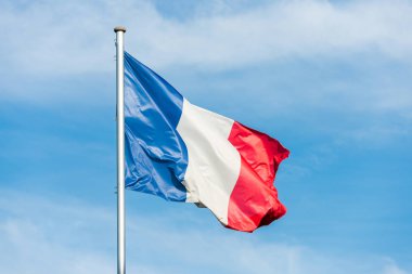 French flag waggling in the wind with sky in background clipart