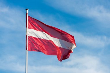 Austrian flag waggling in the wind with sky in background clipart