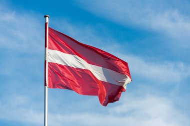 Austrian flag waggling in the wind with sky in background clipart