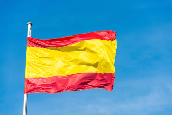 Spanish flag waggling in the wind with sky in background