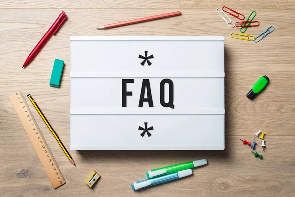 FAQ escrito em lightbox deitado na mesa como flatlay — Fotografia de Stock