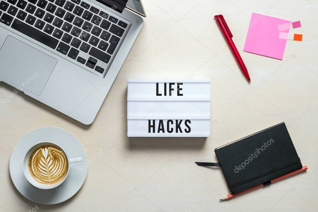 Life hacks written on lightbox in office as flatlay