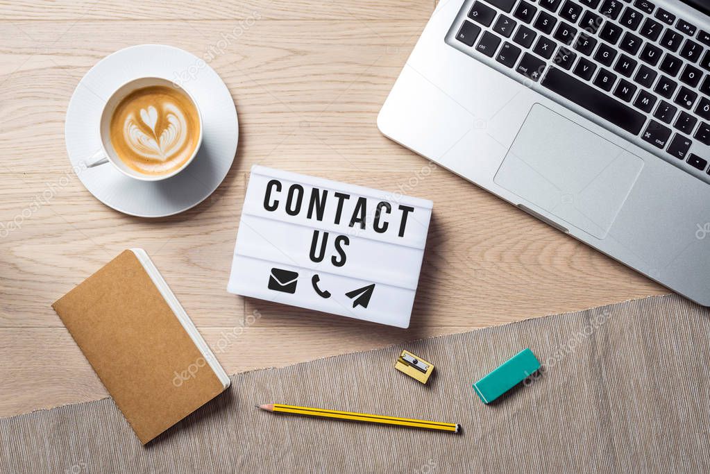 Contact us writing in lightbox lying on desk as flatlay