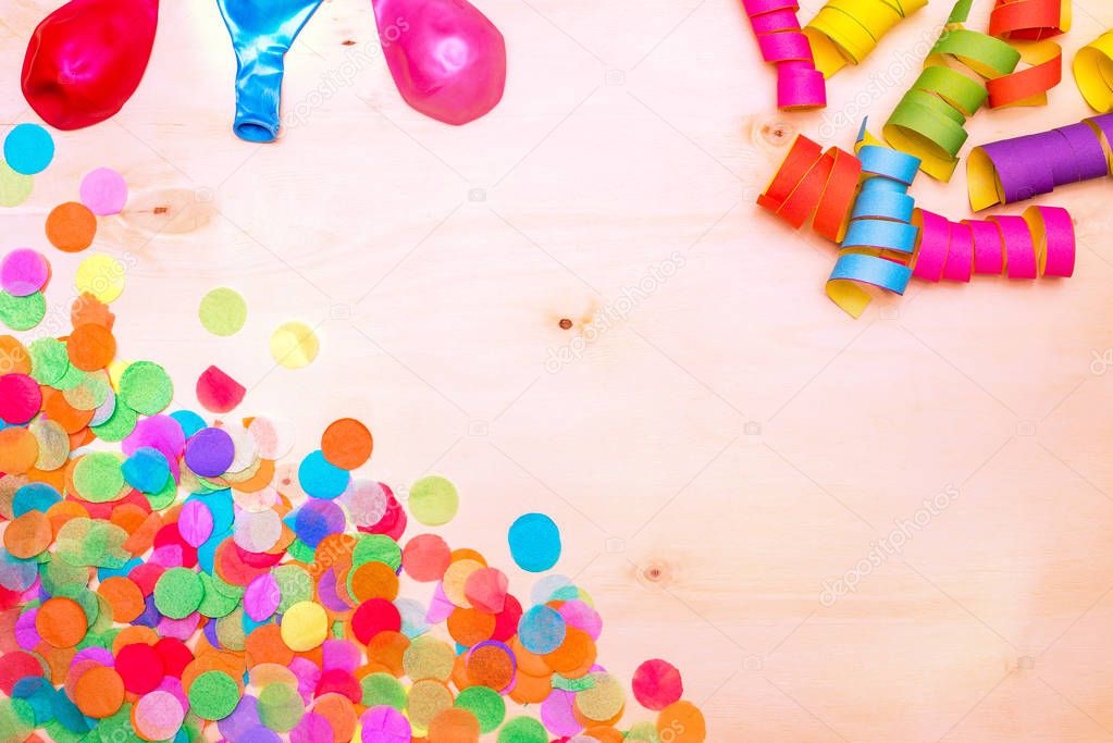 Colorful confetti and streamer on wooden background from above
