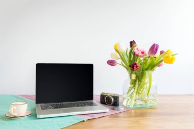 Dizüstü ekran kopya alanı ve çiçeklerle wh ile ahşap masa