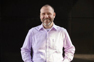 Siyah bir duvara gülümseyen adam