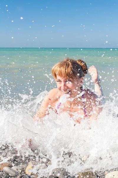 ビーチで波飛沫で美しい少女 — ストック写真