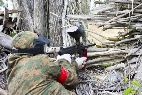 Muž hraje paintball schovává za živý plot v jasný den — Stock fotografie