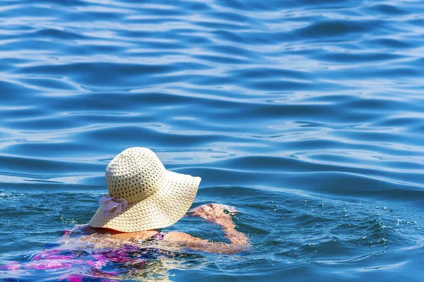Frau mit Hut schwimmt an einem Sommertag im blauen Meer — Stockfoto