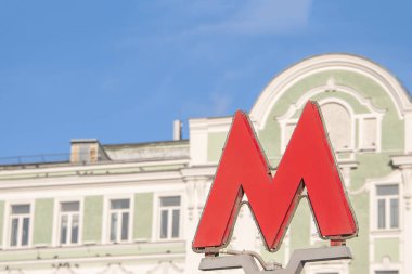 Underground M sign with blurred background in summer day