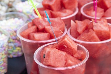Tatlı kırmızı karpuz dilimleri marketin tezgahında bir bardakta şişlerin üzerinde
