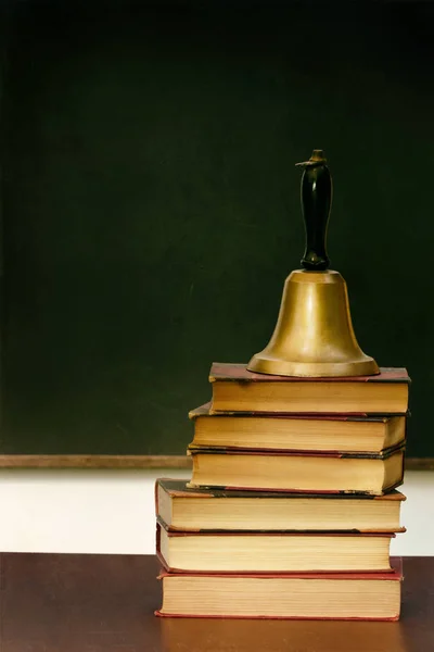 Stapel boeken en school bell op Bureau — Stockfoto