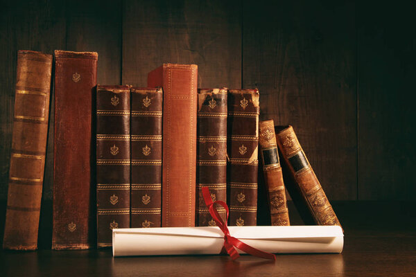 Stack of old books with diploma on desk