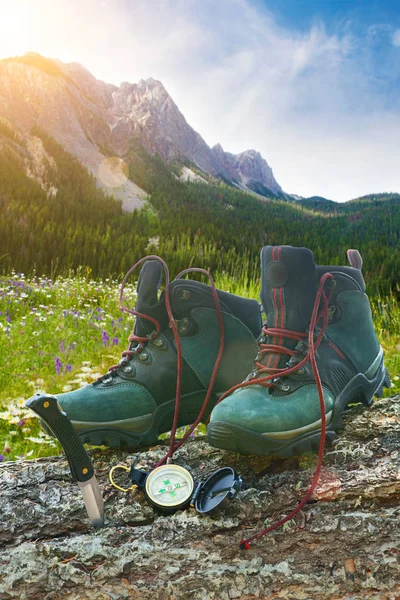 Hiking boots with knife on tree trunk — Stock Photo, Image