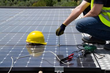 fitting photovoltaic panels on a roof  of a building clipart