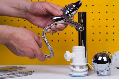 Tesisatçı anda onun tezgah üzerinde boruları tamir