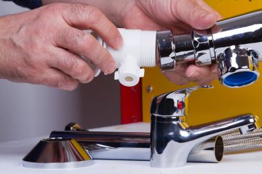 Tesisatçı anda onun tezgah üzerinde boruları tamir