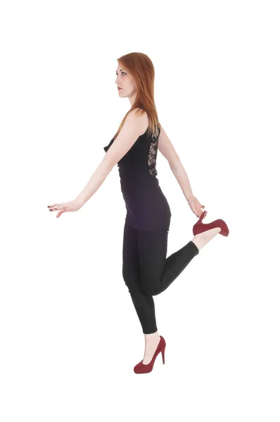 Kobieta stojąc na jednej nodze trzyma obcasy — Zdjęcie stockowe