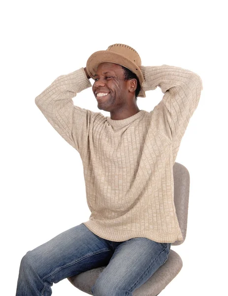 Glad ung afrikansk man sitter med hatt — Stockfoto