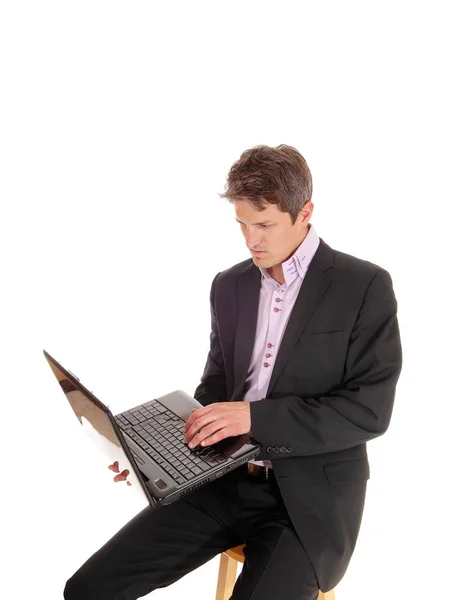Деловой человек сидит и работает над своим ноутбуком — стоковое фото