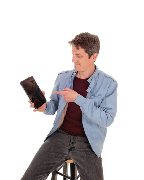 Young man sitting on chair pointing to his tablet — Stock Photo, Image