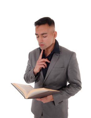 Genç adam ayakta kitap okuyor.