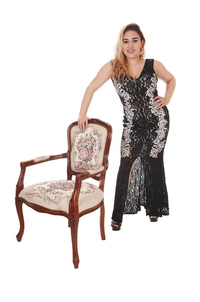 Beautiful woman standing with an antic armchair — Stock Photo, Image