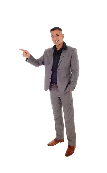 Young man standing in gray suit pointing with finger — Stock Photo, Image