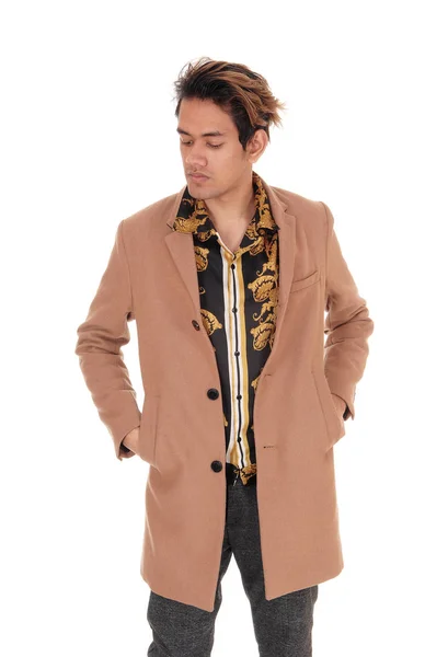 Young man standing with his beige coat in the studio — Stock Photo, Image