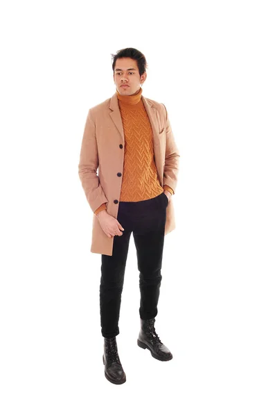 Wysoki młodzieniec stojący w beżowym płaszczu w studio — Zdjęcie stockowe