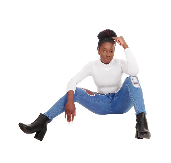 Pretty African female sitting on the floor in jeans — Stock Photo, Image