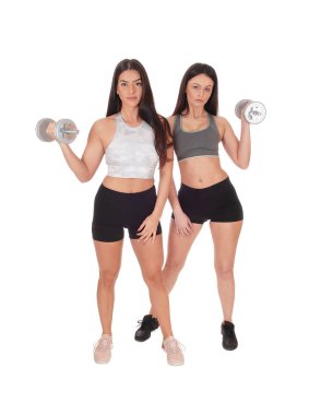 İki kadın stüdyoda dambıllarla egzersiz yapıyor.