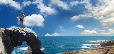 Kız güzel manzaralı bir kayanın üzerinde duruyor.