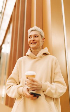 Happy woman with tea and cellphone