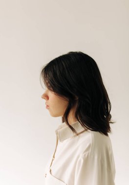 Beyaz arka planda esmer genç bir kadının portresi.