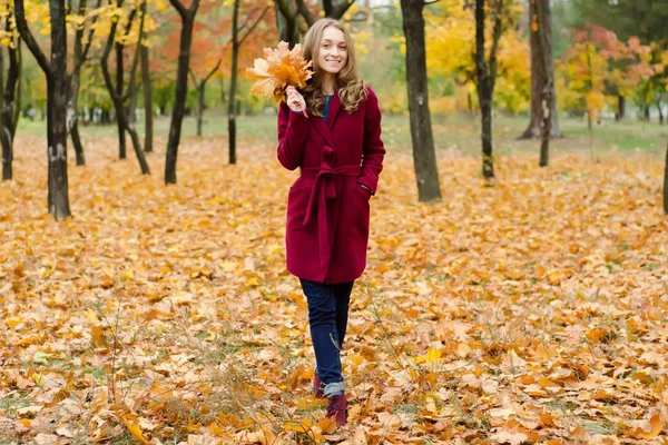 Woman in a coat bouquet of orange leaves in hand — Stock Photo, Image