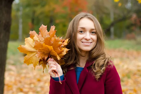 Mujer en un ramo de abrigo de hojas de color naranja en la mano —  Fotos de Stock