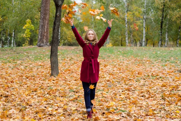 Mulher bonita em um parque de casaco folhas de outono voar — Fotografia de Stock