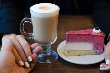 Erkek kadın elinde köpük ve pasta ile kahve latte