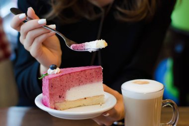 Genç güzel kadın tablo kek üzerine köpük sütlü kahve içer